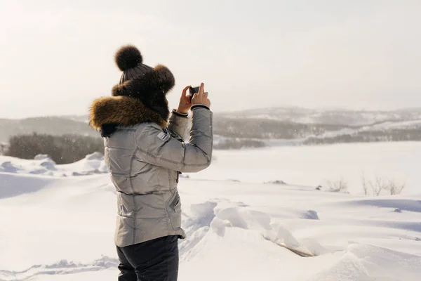 Vrouw in winter pak fotograferen sneeuw bedekte veld — Stockfoto