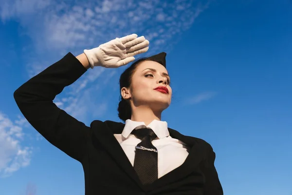 Стюардесса в форме позирует на фоне неба — стоковое фото