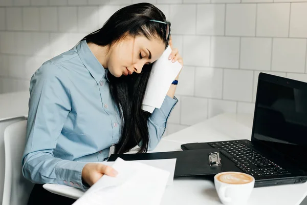 Втомилася жінка сидить за столом в офісі — стокове фото