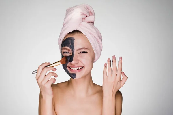Happy woman with a towel on her head puts on face mask — Stock Photo, Image