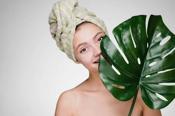 Mulher feliz com uma toalha na cabeça segurando um lençol de uma planta — Fotografia de Stock