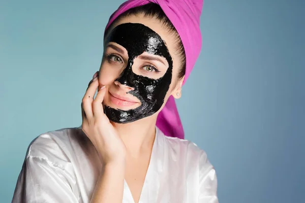 Boldog nő egy törülköző a fején alkalmazni egy tisztító maszk az arcbőrre — Stock Fotó