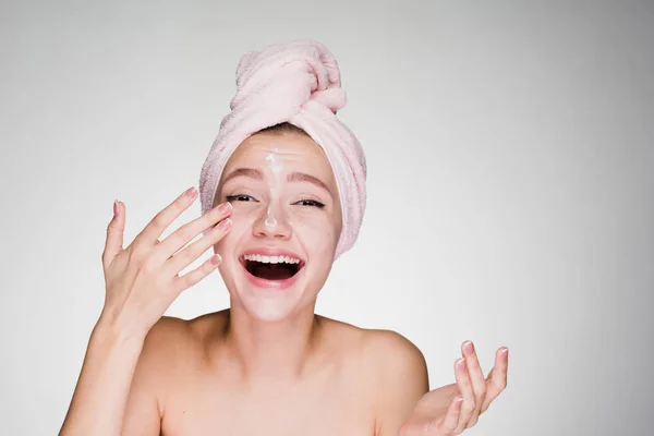 Happy woman with a towel on her head applied cream on face — Stock Photo, Image