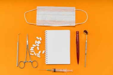 hap, defter ve diş aletleri turuncu bir arka plan üzerinde yatıyor