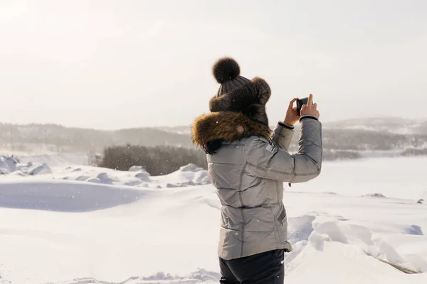 Kobieta w Czapka zimowa fotografowanie zaśnieżone pola — Zdjęcie stockowe