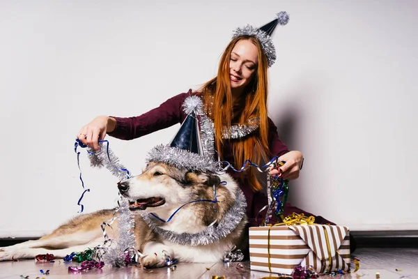 Счастливая женщина в праздничной кепке сидит рядом с большой собакой — стоковое фото