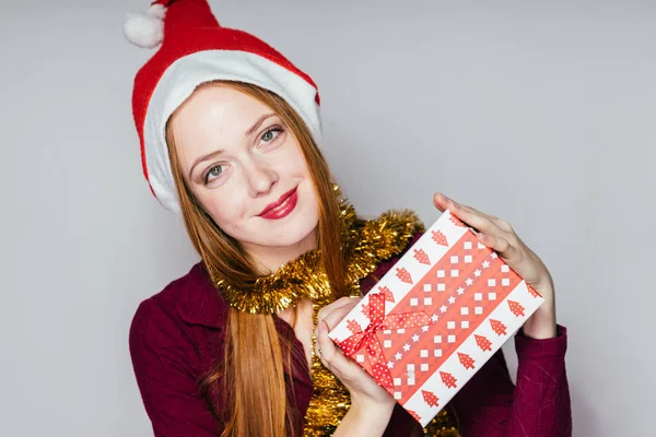 Frau mit Weihnachtsmütze hält Geschenk in den Händen — Stockfoto
