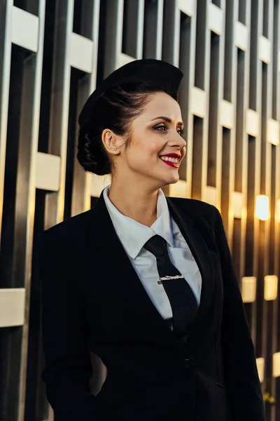 Šťastná žena letuška v jednotné pózuje na budování pozadí — Stock fotografie