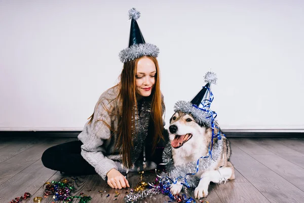 Собака в праздничной кепке сидит рядом с женщиной — стоковое фото