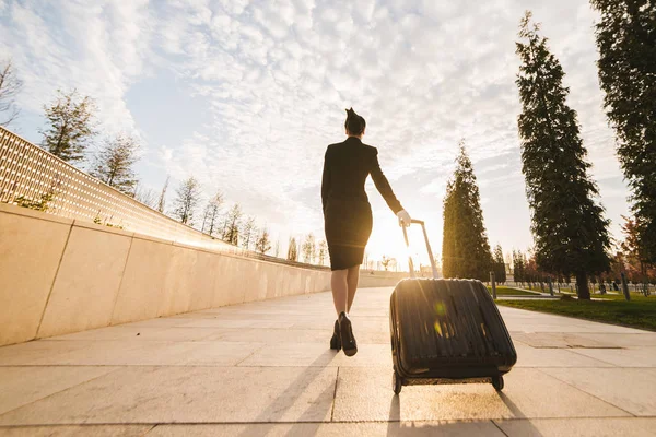 Nő a repülés stewardess hordoz egy nagy bőröndöt — Stock Fotó