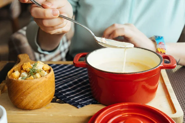 A woman is sitting at a table and eating a soup with croutons — Stock Image A woman is sitting at a table and eating a soup with croutons Stock Picture