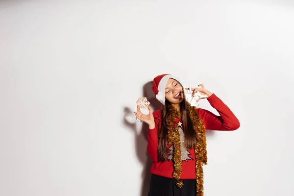 Ευτυχισμένη γυναίκα σε ένα νέο έτος καπέλο κρατά στα χέρια της διακοσμήσεις Χριστουγέννων — Φωτογραφία Αρχείου