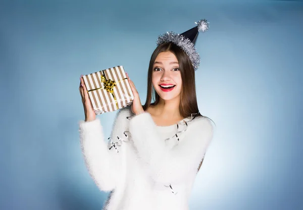 Gelukkige vrouw in een feestelijke hoed houdt een geschenk in haar handen — Stockfoto