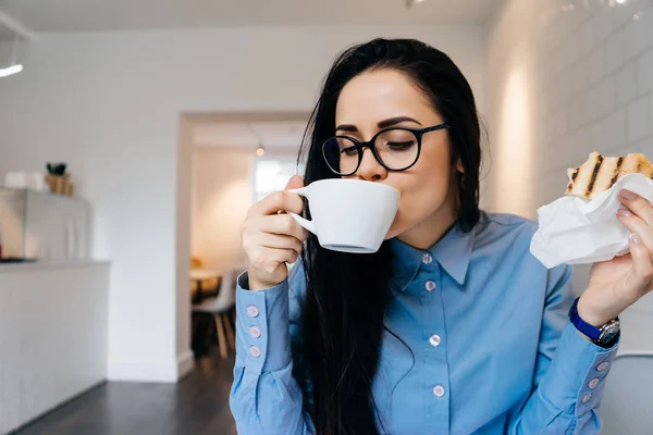 Obchodní žena sedí v kanceláři na stůl a pití kávy — Stock fotografie