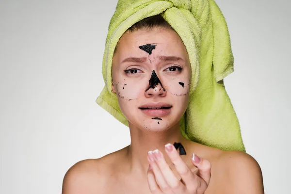 A frustrated woman with a towel on her head took off the cleansing mask from her face — Stock Photo, Image