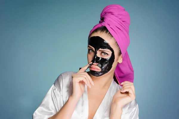 Nő fején egy törülközővel alkalmazott egy maszk a bőr az arcán — Stock Fotó