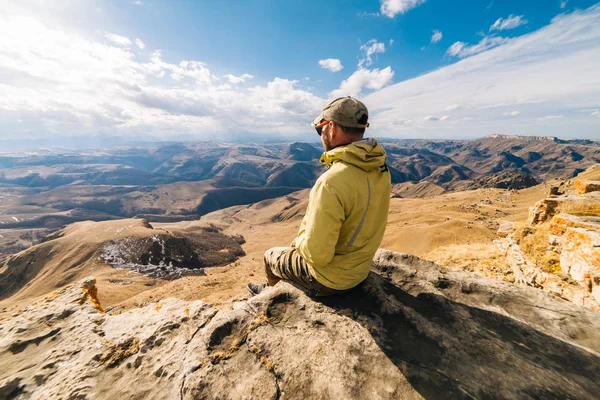 Erkek turist yüksek dağlar bir arka plan üzerinde oturuyor — Stok fotoğraf