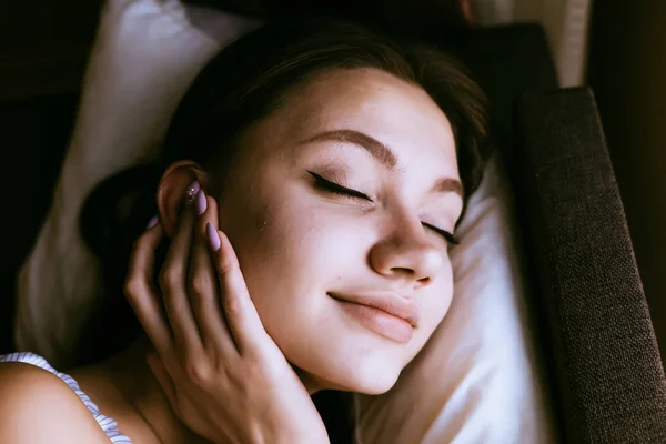 Frau schläft auf dem Bett und setzt sich Kopfhörer in die Ohren — Stockfoto