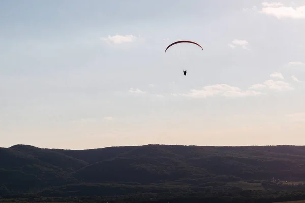 Un hombre en un paracaídas desciende al fondo de las montañas — Foto de Stock