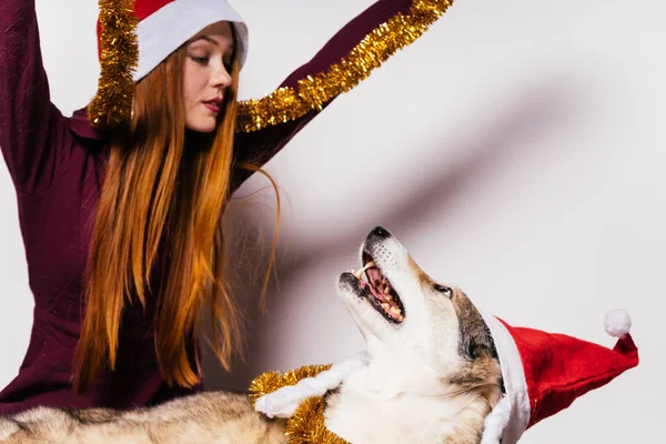 Woman in a Christmas hat playing with a dog — Stock Photo, Image