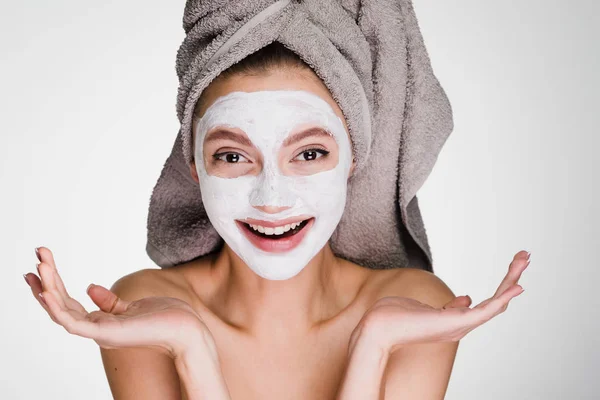 Szczęśliwa kobieta z ręcznikiem na głowie zastosować maskę na oczyszczoną skórę twarzy — Zdjęcie stockowe