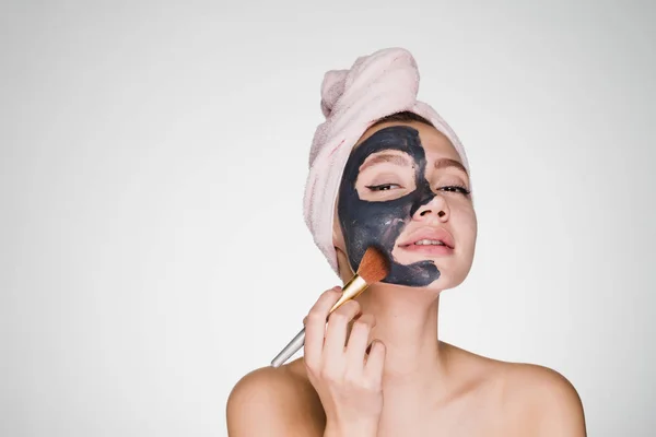 Nő fején egy törülközővel vonatkozik a tisztító maszk az arcán — Stock Fotó