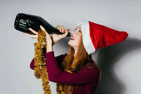 Glückliche Frau mit Weihnachtsmütze hält eine Flasche in der Hand — Stockfoto