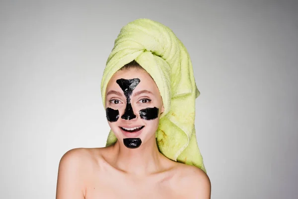 Happy woman with a towel on her head applied a mask to problem areas of the skin — Stock Photo, Image