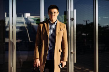 Kendine güvenen Asya delikanlı ile gözlük ve güneş altında poz şık bej bir palto