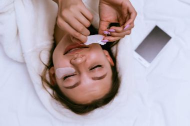 sevimli genç kız beyaz bir elbise içinde bir yatakta yatıyor, gözlerinin altında beyaz lekeler tutkallar