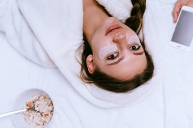 sevimli genç kız beyaz bir elbise içinde beyaz lekeler gözlerinin altında bir yatakta yatıyor