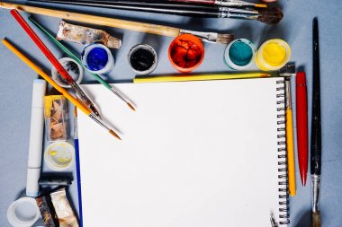 mavi bir masada sanat malzemeleri, teknik inceleme ve birçok fırçaları vardır