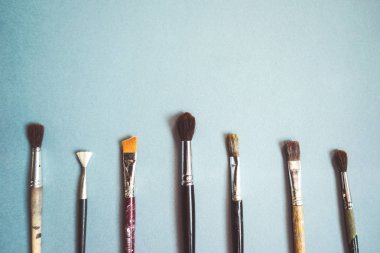 mavi bir masada sanatsal fırçaların farklı boyutlarda vardır