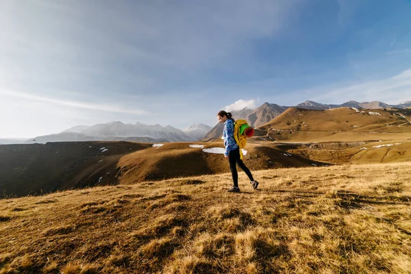 Attiva ragazza in giacca blu viaggia attraverso le montagne del Caucaso con uno zaino e una tenda — Foto Stock