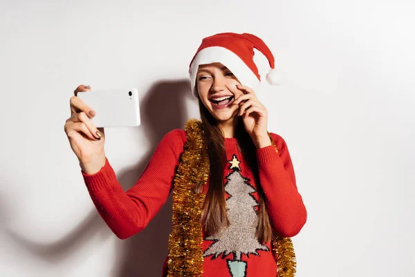 Lustiges junges Mädchen in roter Mütze und Pullover macht Selfie — Stockfoto