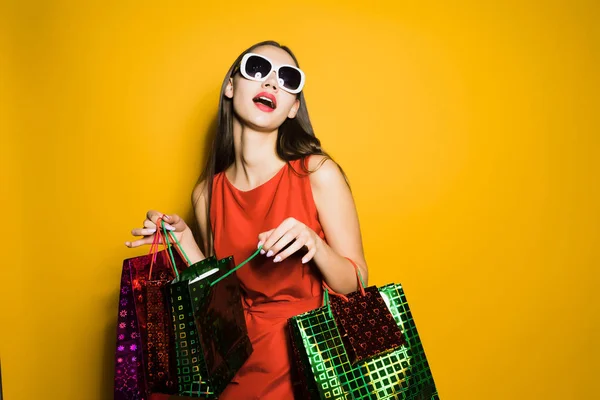 年轻迷人的女孩在红色礼服和太阳镜去购物 — 图库照片