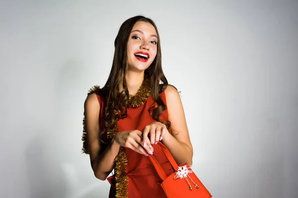 Счастливая красивая девушка в красном платье получил подарок в качестве дорогой сумки — стоковое фото