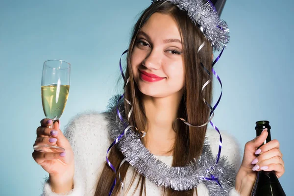 Счастливая молодая девушка празднует Новый год и Рождество, держа в руках бокал и бутылку шампанского — стоковое фото