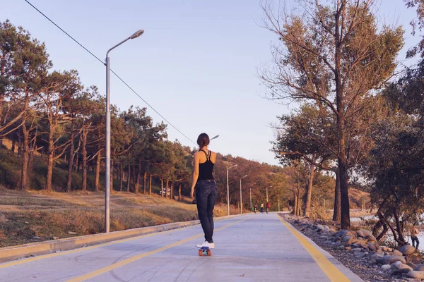 Aktiv ung flicka rider en longboard på en tom väg — Stockfoto