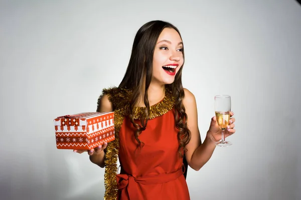 Счастливая смеющаяся девушка празднует Новый год, держа в руках бокал шампанского и подарок — стоковое фото