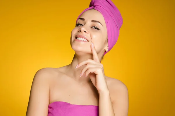 Felice ragazza sorridente con un asciugamano rosa sulla testa pensando alla bellezza — Foto Stock