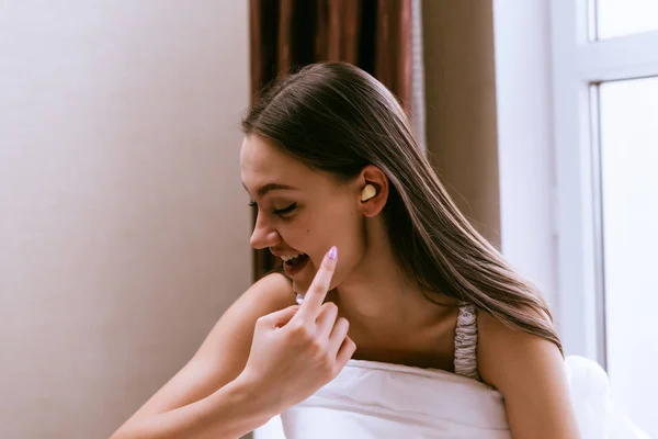 Милая улыбающаяся девушка показывает большой палец на затычки для ушей против уличного шума — стоковое фото