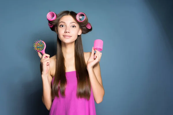 Χαριτωμένο νεαρή κοπέλα κρατώντας μια χτένα, το κεφάλι μεγάλο ροζ σίδερα — Φωτογραφία Αρχείου