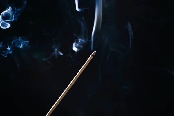 В темноте тлеет палочка аромата, синий дым — стоковое фото