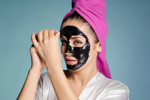 Szép, fiatal lány, egy rózsaszín törülközővel a fejét a fekete maszk eltávolítása az arcát — Stock Fotó