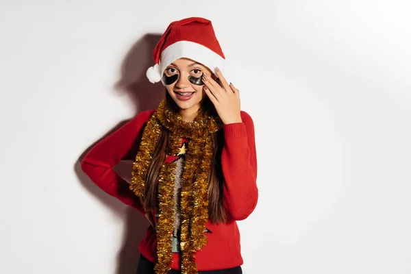 Menina feliz em uma camisola vermelha e boné celebra o ano novo, sob os olhos de manchas pretas — Fotografia de Stock