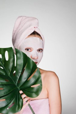 bir kadın duş sonra başında bir havlu ile yüz maskesinin koymak