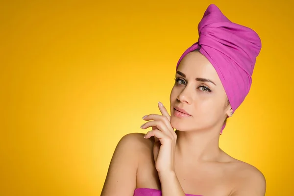 Woman with a towel on her head after a shower on a yellow background — Stock Photo, Image