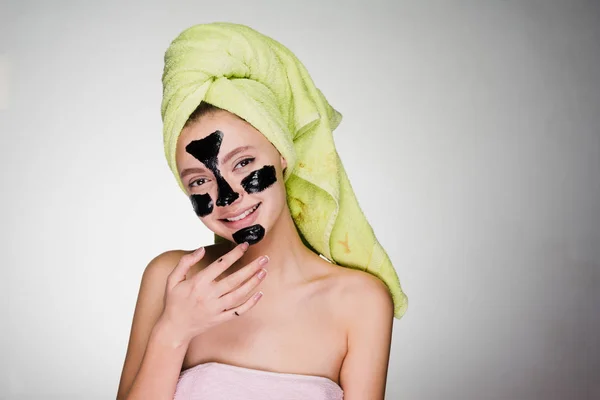 Happy woman with a towel on her head after showering the mask on problem areas of the face — Stock Photo, Image