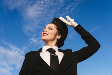 mutlu kadın hostes gökyüzü arka plan üzerinde üniformalı